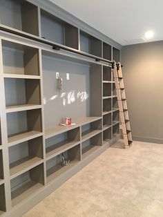 an empty room with shelves and ladders in it