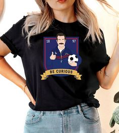 This "Be Curious" design is the perfect, fun Ted Lasso shirt for anyone that loves sports and Ted Lasso! Sports T-shirt With Character Print And Crew Neck, Funny Crew Neck Sports T-shirt, Crew Neck Tops With Character Print For Sports Events, Crew Neck T-shirt With Character Print For Sports Events, Ted Lasso Shirt, Soccer Nails, Ugly Christmas Sweater Couples, Ted Lasso, Christmas Sweater Party