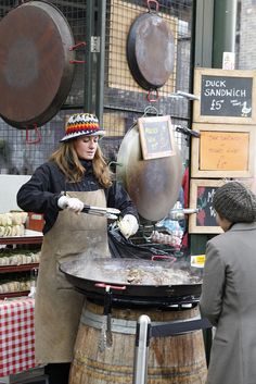 a woman cooking food on an outdoor grill