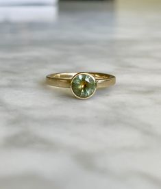 One of a kind engagement ring custom-designed and made in December 2020 in Portland, Oregon.  Ring is made of 14k yellow gold (ethically sourced), brushed finish, 2mm x 1.5mm band with bezel set floating .97ct bicolor Montana Sapphire. The bi-color Montana sapphire appears to change color in different light... sometimes it appears as sky blue, sometimes smoky gray, sometimes light teal...  and there is an orange flame color centered within the sapphire.  The gem is truly stunning, and hard to de Teal Ring, Teal Rings, Montana Sapphire Engagement, Montana Sapphire Engagement Ring, Engagement Ring Size, Montana Sapphire, Sapphire Engagement Ring, Light Teal, Sapphire Engagement