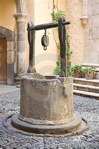 an old fashioned water well in the middle of a cobblestone street