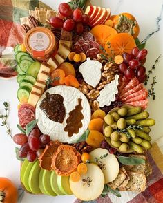 a platter filled with lots of different types of fruit and cheese on top of a checkered table cloth