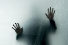 a blurry image of someone's hands reaching out from behind a frosted glass wall