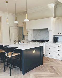 a kitchen with white cabinets and an island in the middle, surrounded by wooden flooring