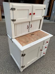 an old white wooden cabinet with red knobs