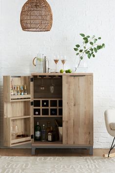 a wooden cabinet with bottles and glasses on it in front of a white brick wall