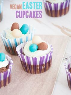 cupcakes with white frosting and chocolate eggs in them on a cutting board