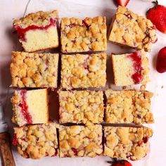 strawberry crumb bars cut into squares on a cutting board with strawberries around them