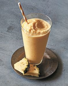 a smoothie and some pieces of pineapple on a plate