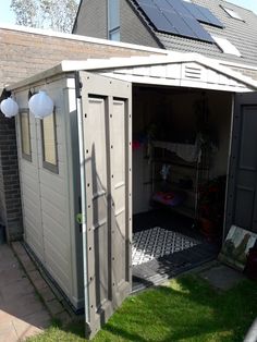 an outdoor storage shed with solar panels on the roof and doors open to reveal a bed