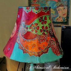 a colorful lamp shade sitting on top of a table next to a wall mounted painting