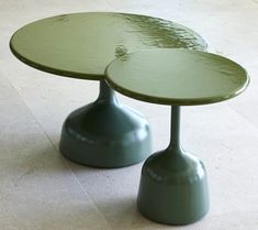 two green tables sitting on top of a tiled floor