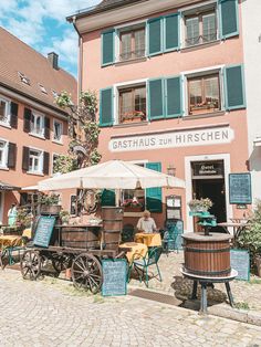 an outdoor cafe with tables and umbrellas in front of it