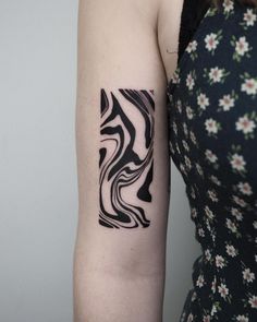 a woman with a black and white tattoo on her arm, wearing a floral dress