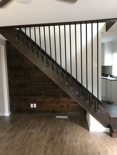 an empty living room with wood floors and metal railings on the stair case,