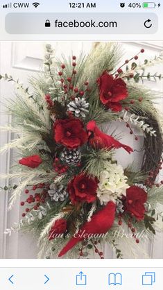 a wreath with red and white flowers is hanging on a door handle, decorated with pine cones