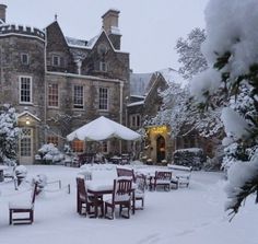 a large building covered in snow with tables and chairs set up on the front lawn