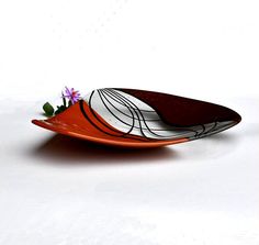 an orange plate with flowers in it on a white surface