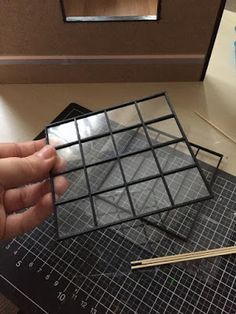 a person is holding up a piece of black paper that has been cut into squares