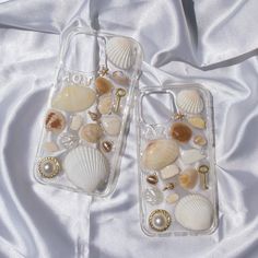 two clear cases with shells and pearls on them