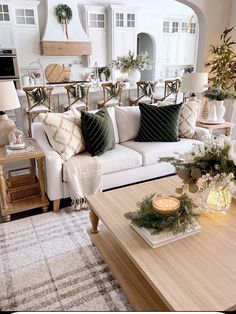 a living room filled with white furniture and lots of greenery on the coffee table