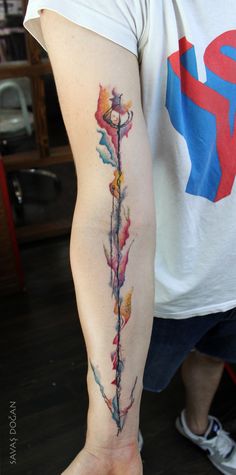 a person with a tattoo on their arm holding a flower in one hand and an arrow in the other