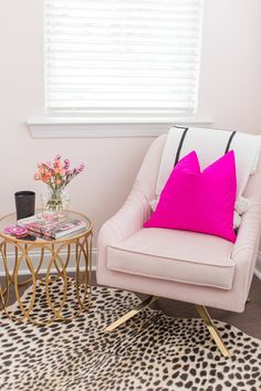 a living room with leopard print rug, pink chair and coffee table in front of the window