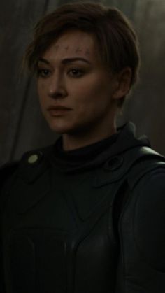 a woman in a black leather outfit looking at the camera