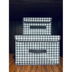 two storage bins sitting on top of a wooden table next to each other in front of a black and white wall