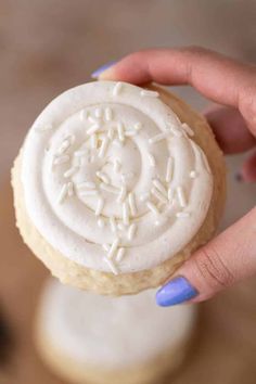 a person holding a frosted cookie in their hand