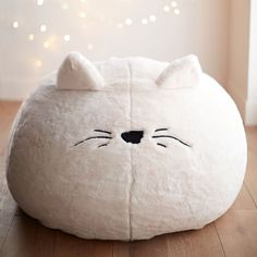 a white cat pillow sitting on top of a wooden floor