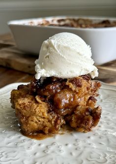 a piece of cake with ice cream on top sits on a plate next to a bowl