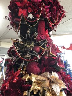 a christmas tree with red and gold decorations on it's top, surrounded by other ornaments