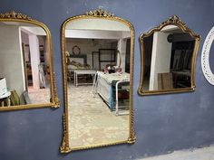 three mirrors hanging on the side of a blue wall next to a table and chairs