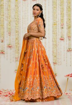 Editor's Note Rust Orange Mirror Thread And Zardosi Embroidered Raw Silk Lehenga. It Is Paired With A Matching Deep Neck Geometric Embroidered Blouse And Pure Silk Dupatta Fabric: Raw Silk, Silk Color: Rust Care: Dry Clean Only About the Designer Sanya Gulati's designs are inspired by the Indian bridesmaids, pastel easy hues & seasonal trends, her designs are a mix of modern, contemporary embroideries with traditional silhouettes thus creating our signature asymmetric checks embroideries amalgam Rust Orange Lehenga, Orange Lehenga, Blouse Yoke, Indian Bridesmaids, Orange Mirror, Raw Silk Lehenga, Wedding Newspaper, Wedding Lehenga Designs, Embroidered Lehenga