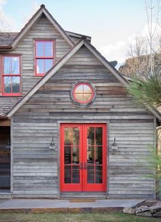 a small wooden house with red doors and windows