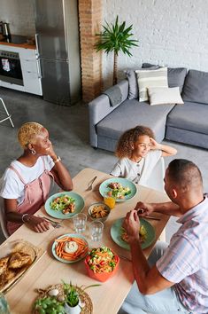 three people sitting at a table with plates of food