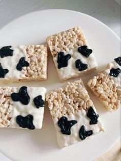 four pieces of rice krispy treats on a white plate with black and white toppings