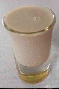 a glass filled with liquid sitting on top of a white tablecloth covered table cloth