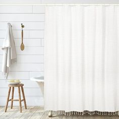 a bathroom with a white shower curtain and wooden stool