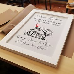 a white frame sitting on top of a table next to a brown box with a red heart