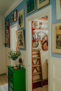 a green cabinet sitting in the middle of a room next to pictures on the wall