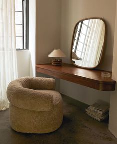 a chair sitting in front of a mirror on top of a wooden table next to a lamp