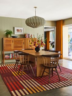 a dining room table with chairs and a rug on the floor in front of it