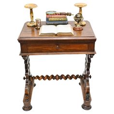 an old wooden desk with books on it and two brass candles next to the table