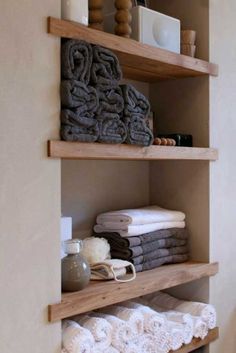 towels are stacked on wooden shelves in the bathroom