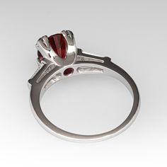 This lovely vintage ring is centered with one (1) round brilliant cut natural rhodolite garnet set into a four-prong setting. The shoulders of the ring are each accented with one (1) channel set, tapered baguette cut diamond. The ring measures 7.6mm at the top, rises 8.1mm above the finger, tapering to 1.2mm wide and 1.1mm thick at the base of the shank. It is currently a size 6.25. Garnet Ring Vintage, Rhodolite Garnet Ring, Ring Mountings, Garnet Ring, Baguette Cut Diamond, Rhodolite Garnet, Channel Set, Baguette Cut, Garnet Rings