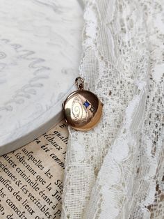 "Beautiful antique gold-plated locket, with a small blue paste stone and a small pearl.  The locket is in overall good antique condition, with some traces of wear and age, consistent with the age of the jewel.  The locket is engraved on the back with a name: \"M Metzger Gonten\". Dimensions: approx. 2.1 x 2.9 cm. Diameter: approx. 2.1 cm.  Colour variations may occur due to the light. The exact colour of the jewel does not come out perfectly in all the photos." Blue Victorian Jewelry With Vintage Charm, Victorian Blue Locket Jewelry, Blue Victorian Locket Jewelry, Antique Blue Locket Jewelry, Vintage Blue Necklace With Pearl Pendant, Locket Gold, Gold Locket, The Jewel, Locket Necklace