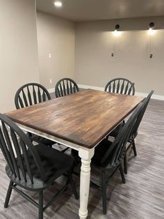 a dining room table with six chairs around it in an empty room that is painted white and has gray walls