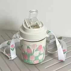 a coffee cup with a white strap around it and a flower design on the side